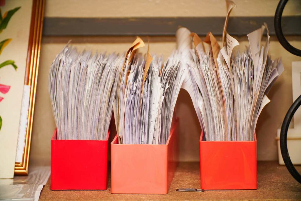 Three red bins stuff full of messy papers