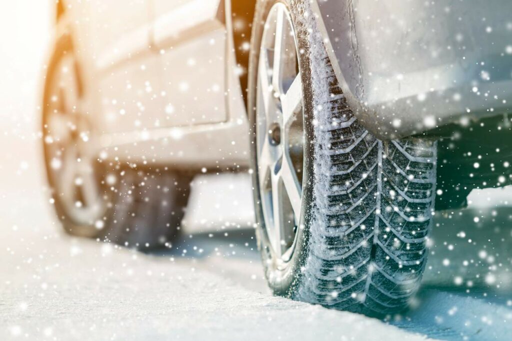 A close-up of the snow-covered tires of a silver car