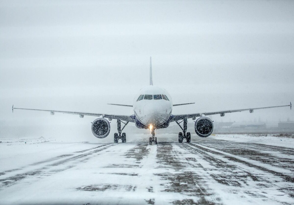 An airplane sits on a snow-covered runway during a snowstorm