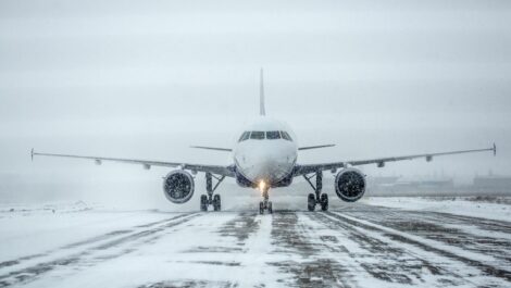 An airplane sits on a snow-covered runway during a snowstorm