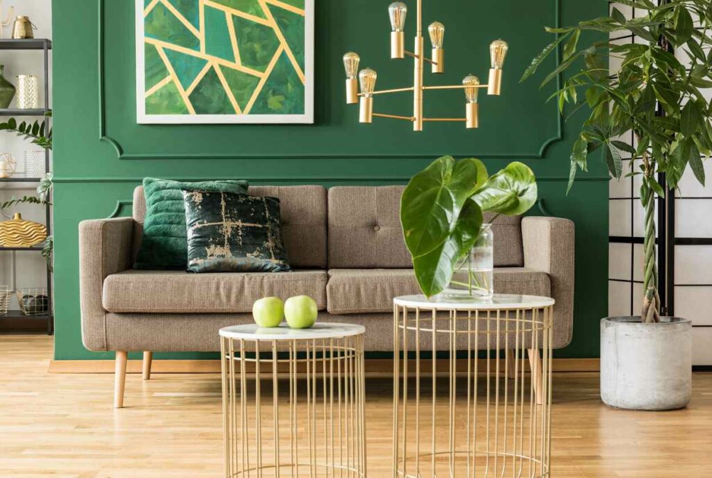  A brown couch and small white and green tables sit in front of a dark green wall