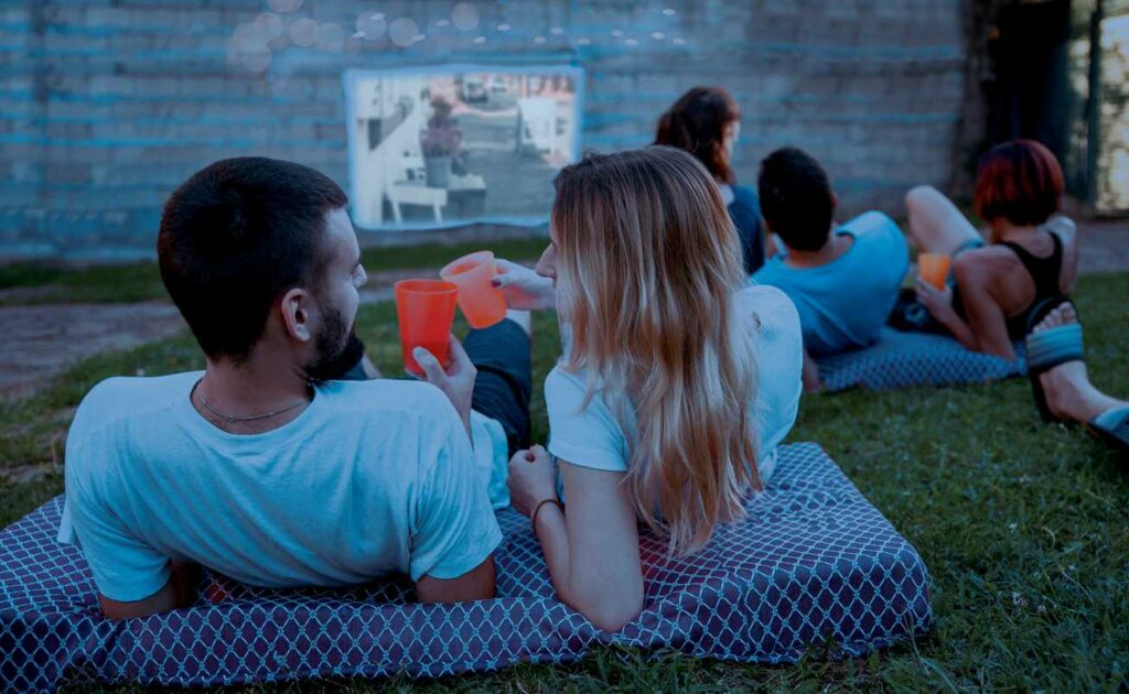 A group in the backyard watching a movie in the grass. 