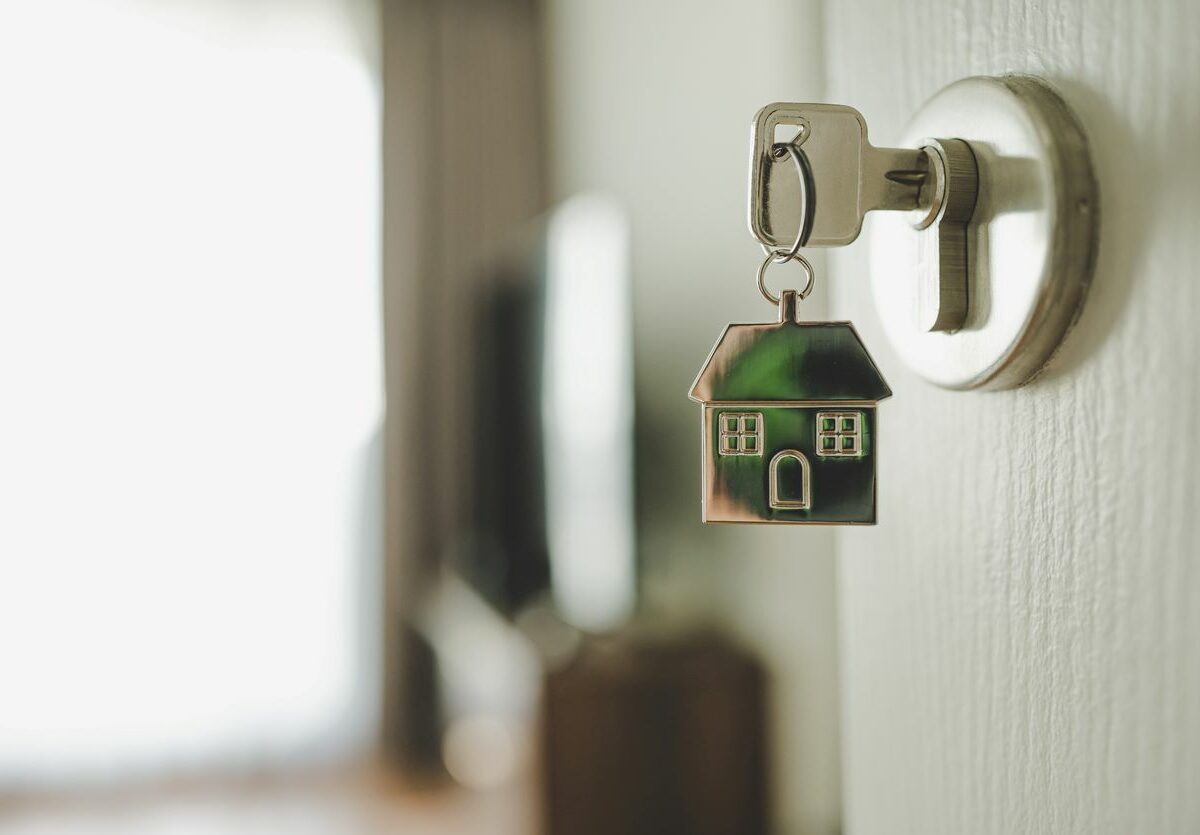 : A key to a new home sitting in the lock on the door with a keychain of a house.