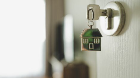 : A key to a new home sitting in the lock on the door with a keychain of a house.