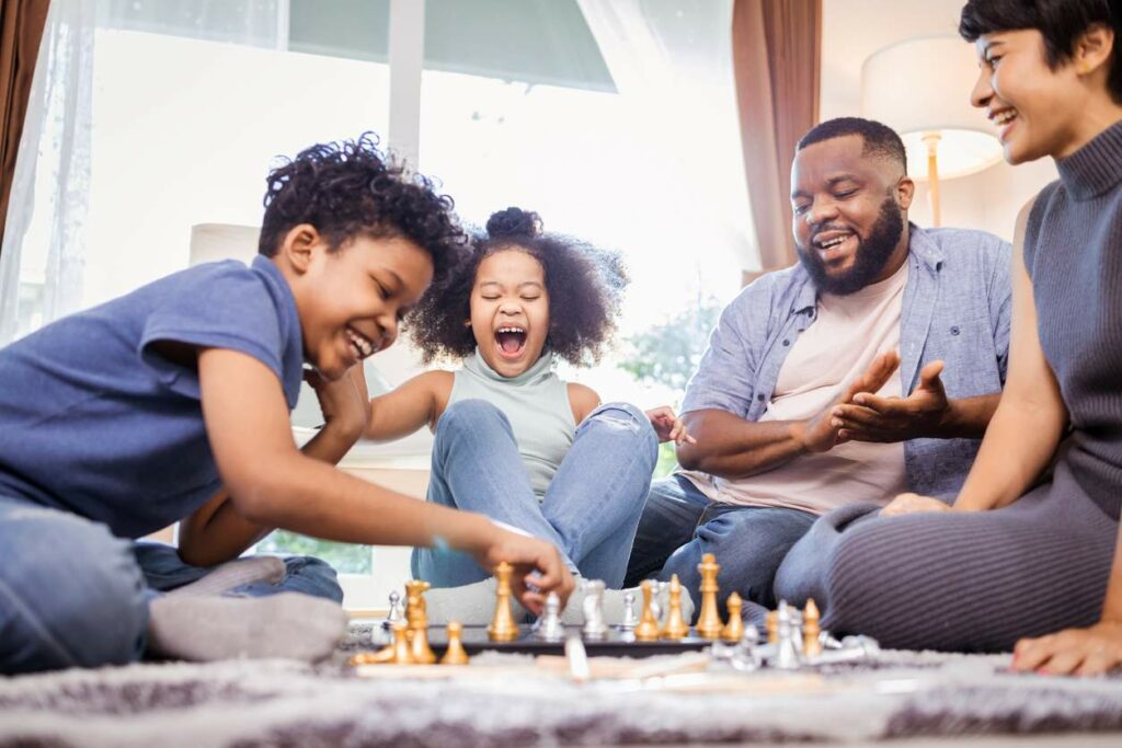  A family laughing while playing chess together