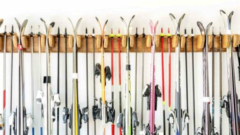 Many sets of skis organized neatly on a hanging rack