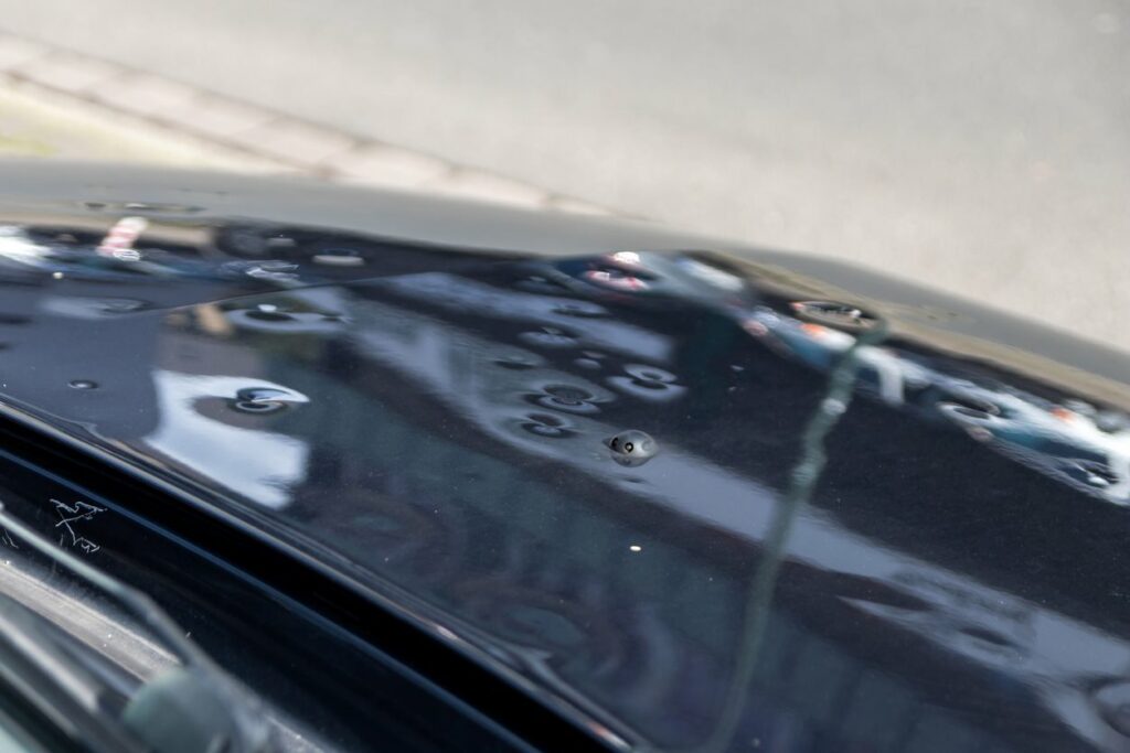 A car with dents in the hood from hail damage