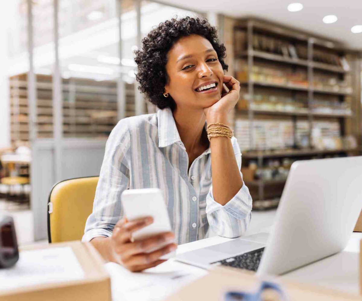 A woman laughing while working on her laptop