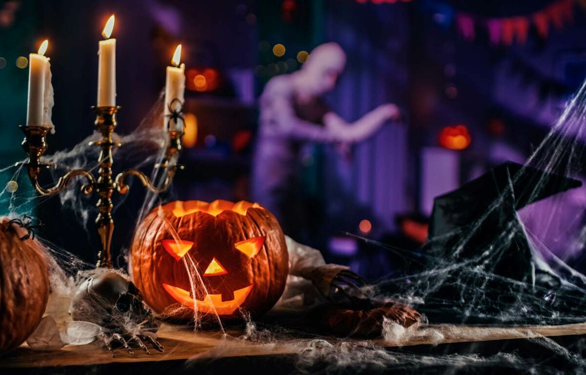 A pumpkin, candelabra, and Halloween decorations covered in cobwebs.