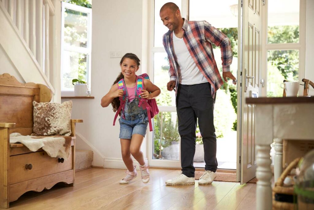 A dad and daughter coming home from school and walking excited into their home.