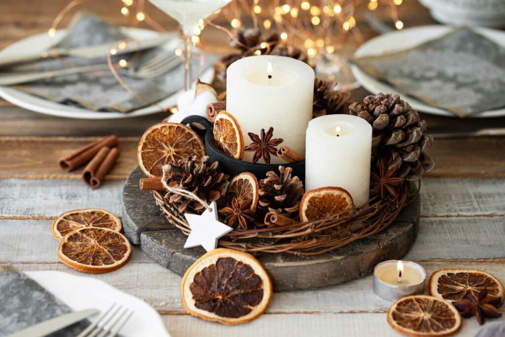 : Array of winter decorations, including candles and pinecones, centered on a wooden dining table. 