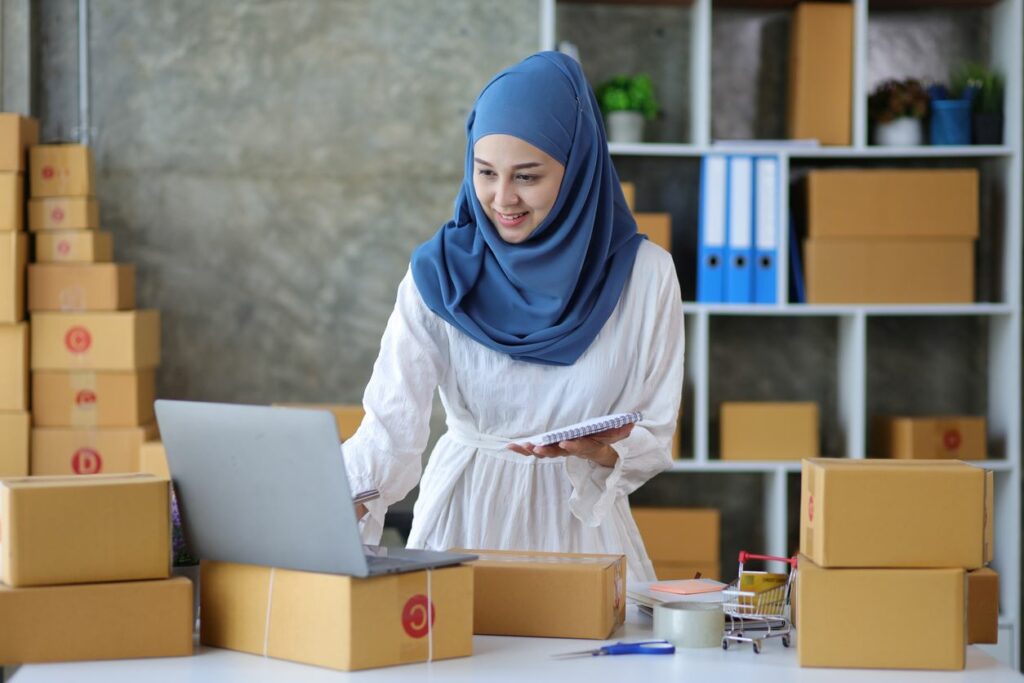 Business owner takes inventory of items using laptop and notepad